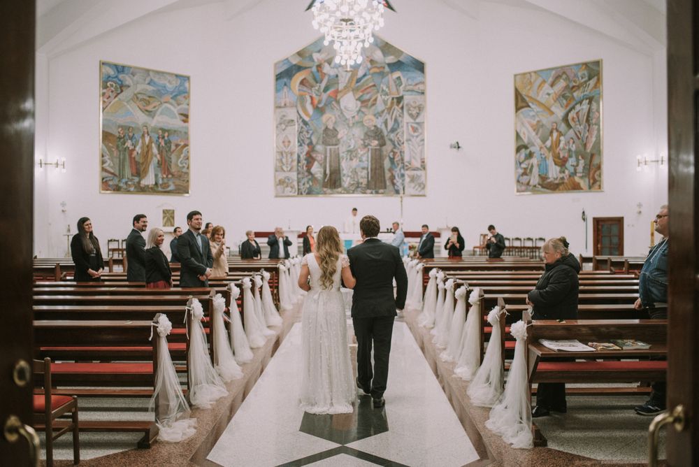 Traditional church interior with religious murals and wooden pews decorated for a wedding ceremony.