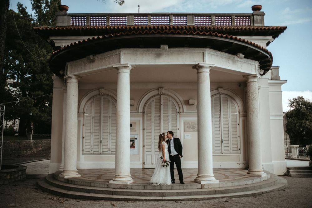 Elegant white neoclassical gazebo with columns creating romantic architectural backdrop.