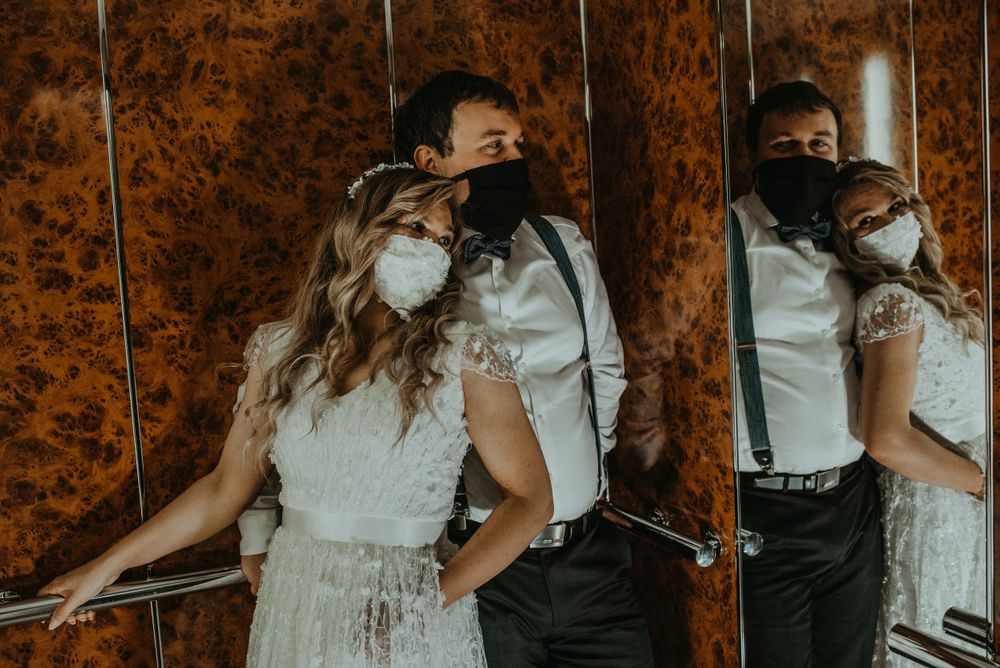 Creative mirror reflection shot showing formal attire and masks in a wood-paneled space.