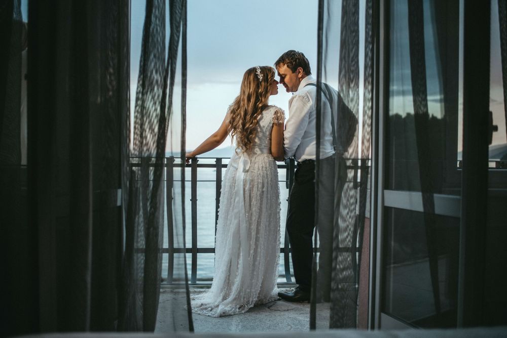 Romantic silhouette against glass doors with curtains in elegant formal attire.