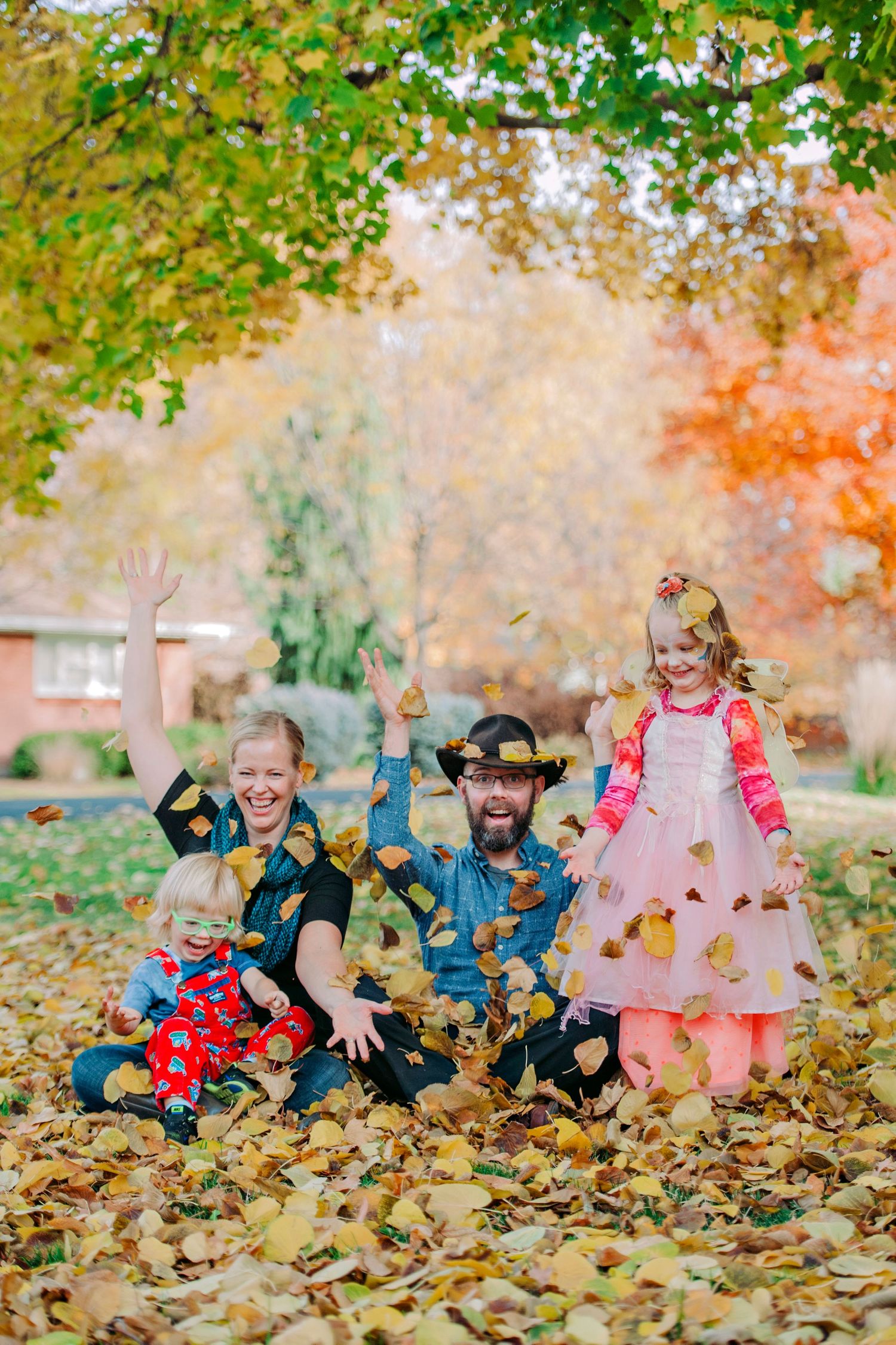A happy family laughs and throws leaves in the backyard