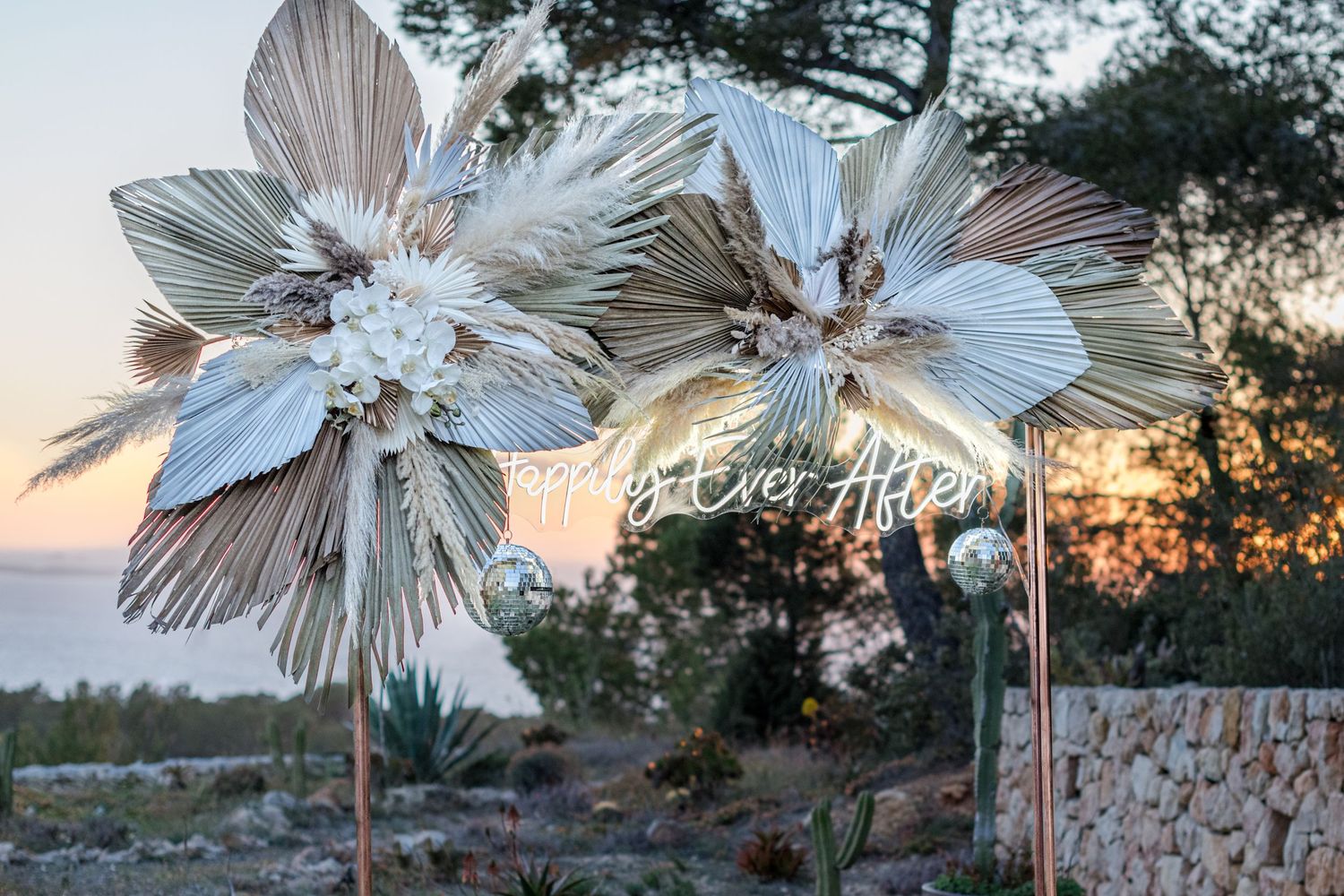 Pampas and palm tree wedding arch that says Happily Ever After