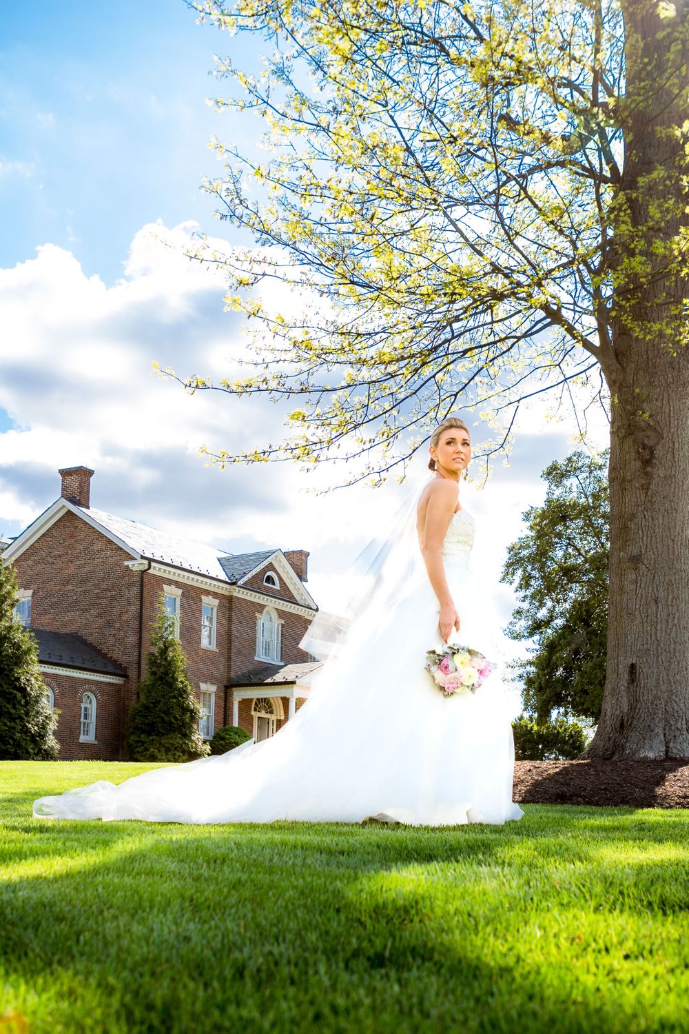 Bride at outdoor wedding venue with stone building and spring trees in Maryland
