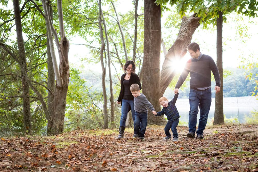 Family walking together under sunlit trees during outdoor portrait session in Maryland