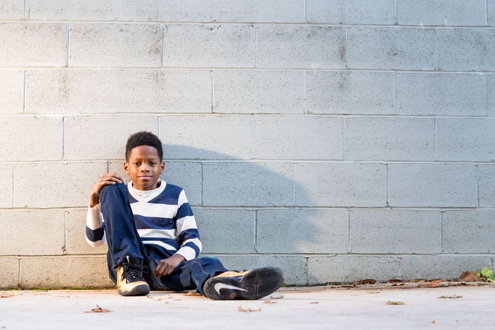 Young boy sitting against concrete wall during family portrait session