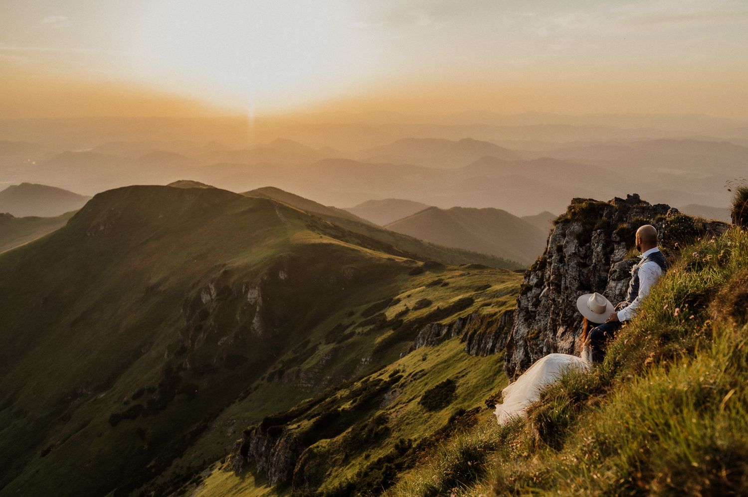 Wedding photo overlooking dramatic mountain landscape at sunset.