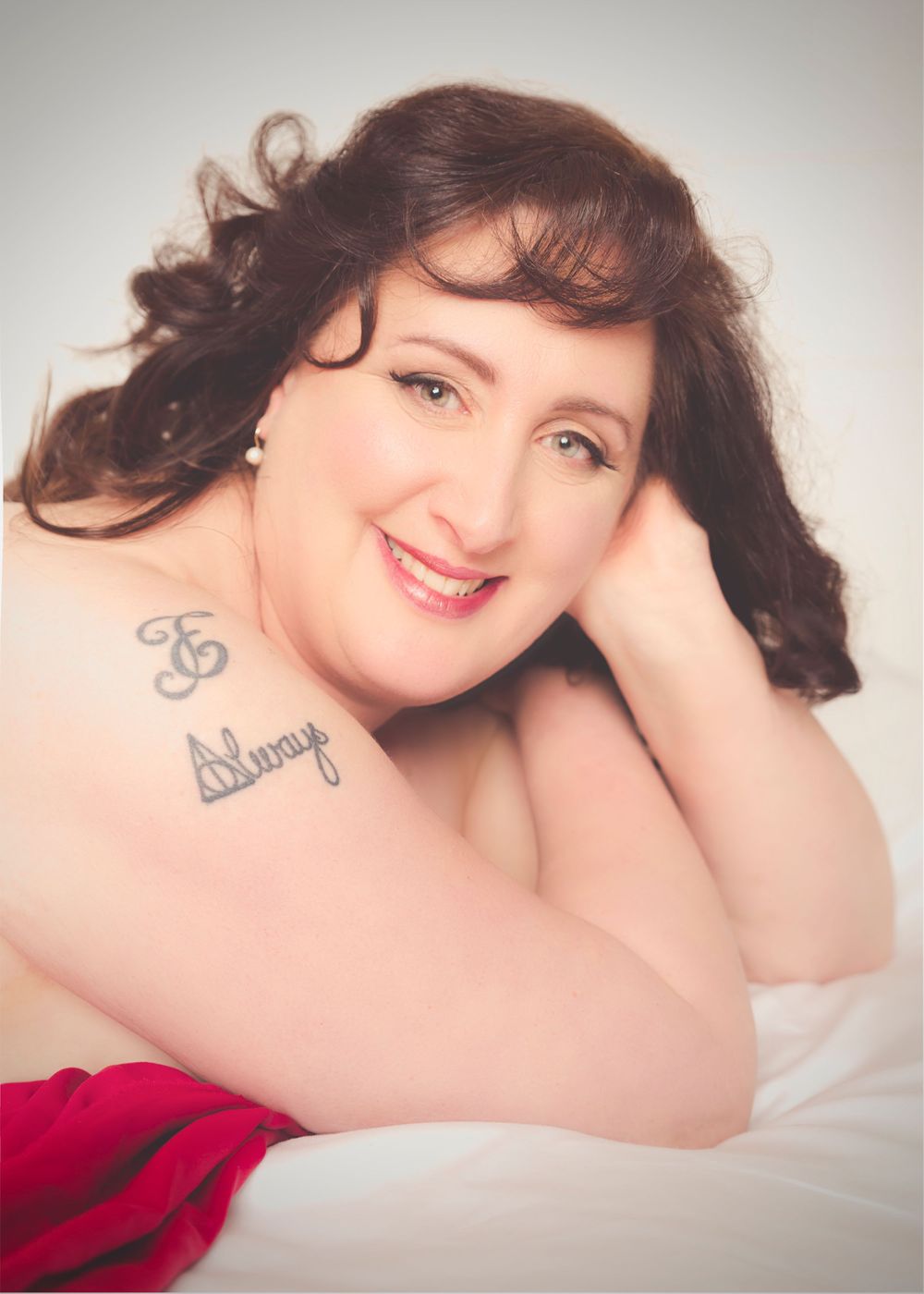 Studio portrait with soft lighting showing shoulders and head against light background.