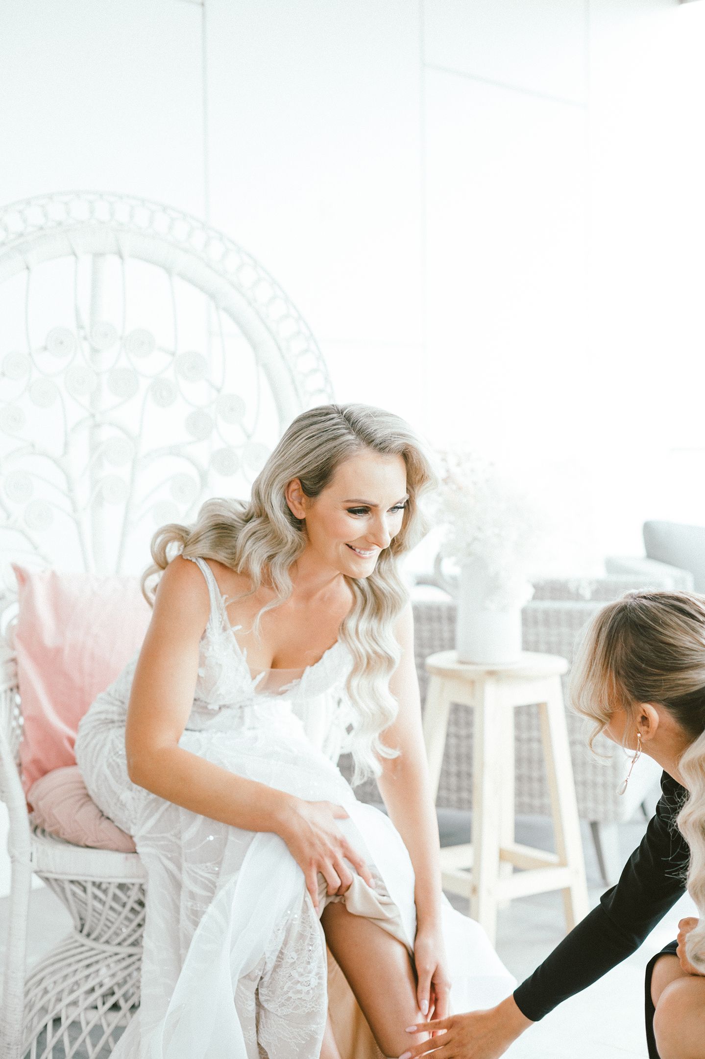 Wedding dress preparations in a bright room featuring decorative white wicker furniture.