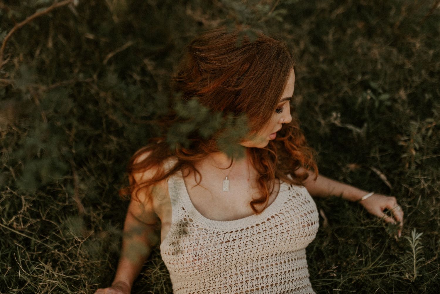 Woman laying in the grass with camera focused on leaves in Mount Isa