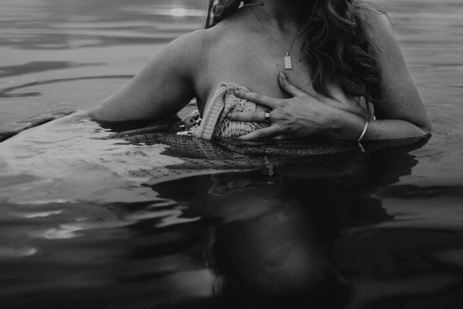 Woman kneeling in water at Lake Moondarra covering her chest with her dress