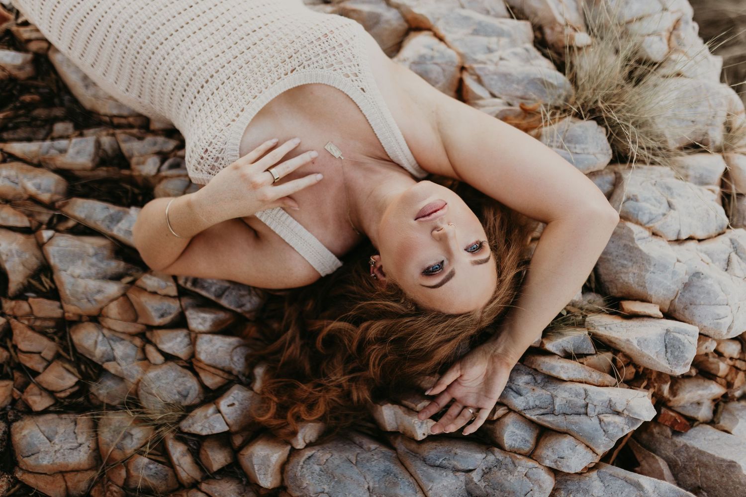 Beautiful woman laying on ground with hand above head and one on chest area