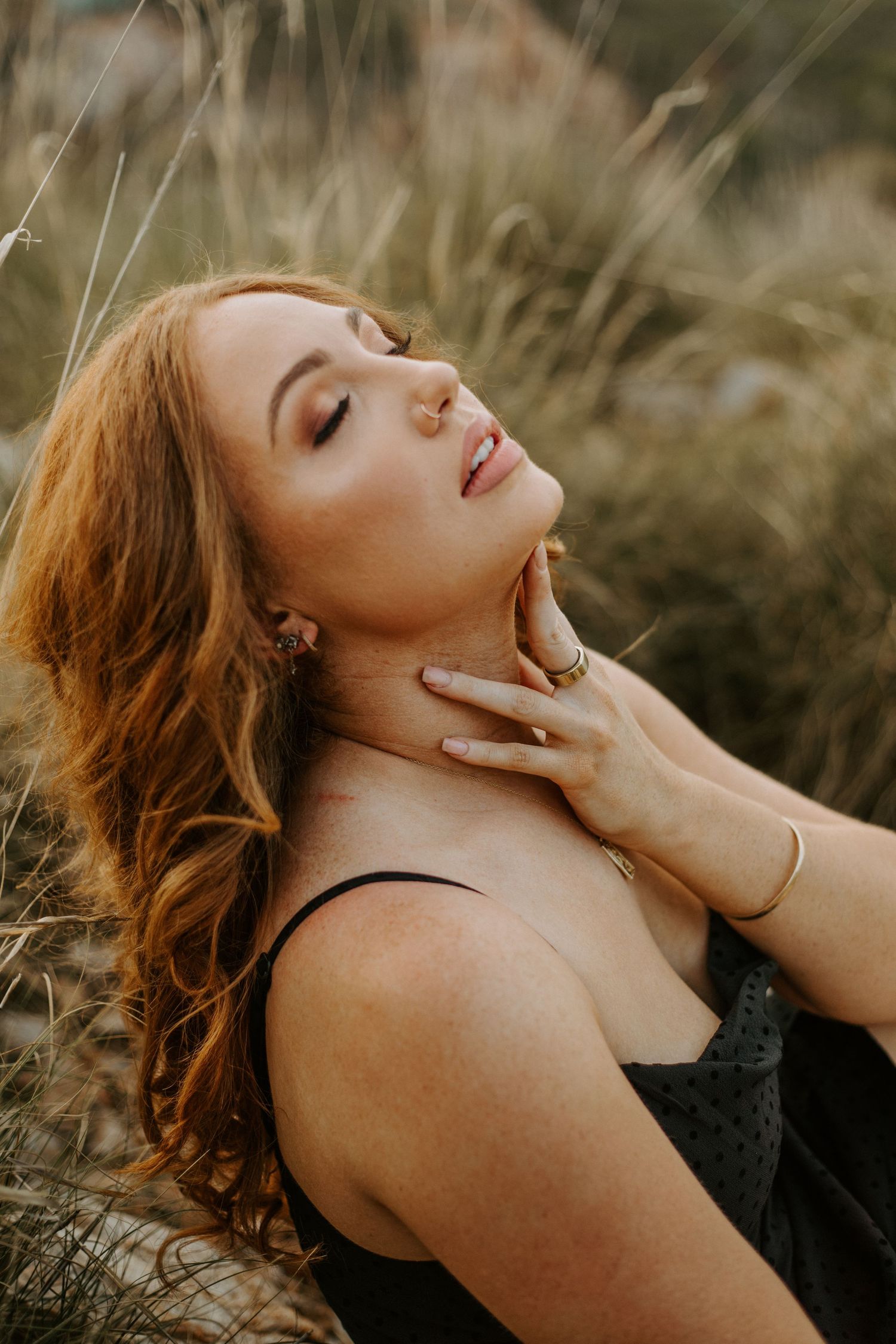 Woman with hand on neck posing in front of hills at Lake Moondarra in Mount Isa