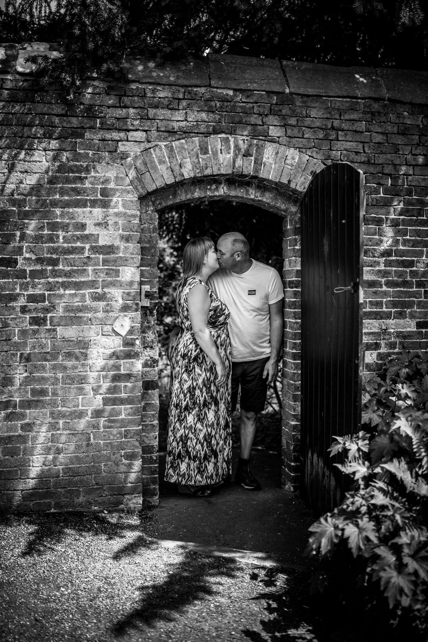 Black and white photos against brick wall showing intimate moments in an archway.