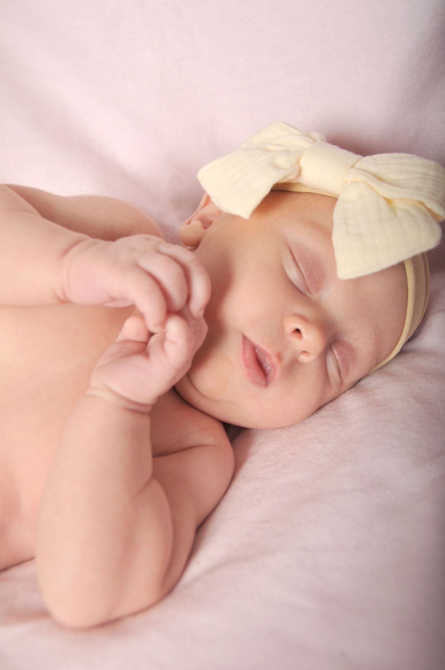Sleeping newborn girl on soft pink blanket