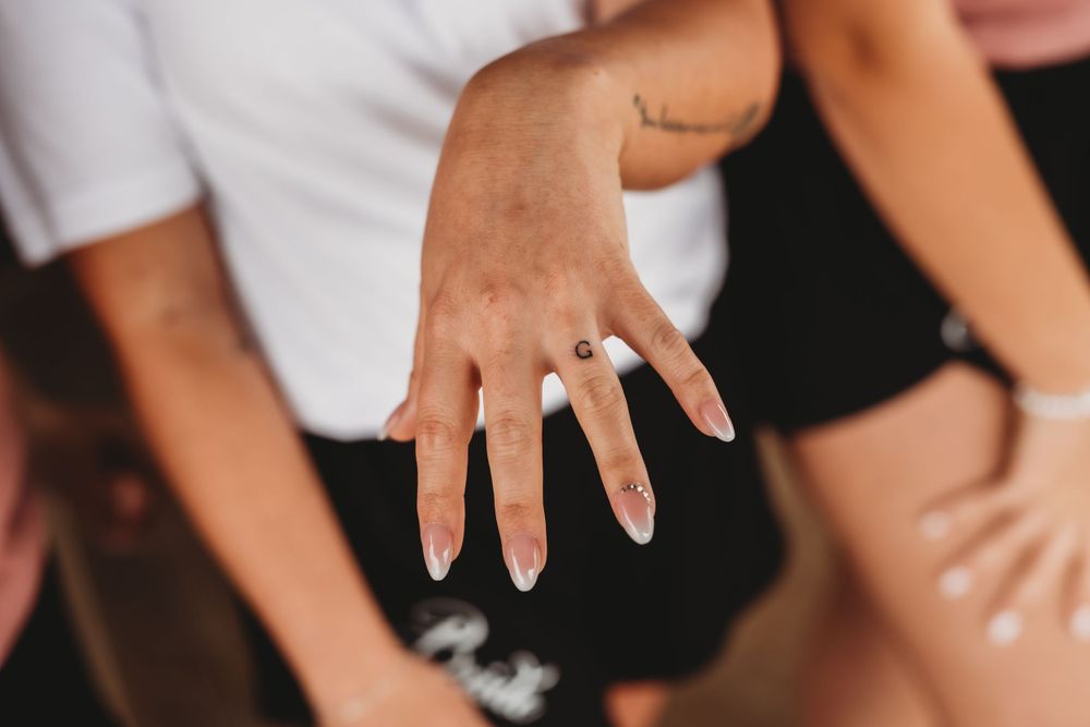 Close-up shot of a diamond engagement ring on a hand against a dark background.