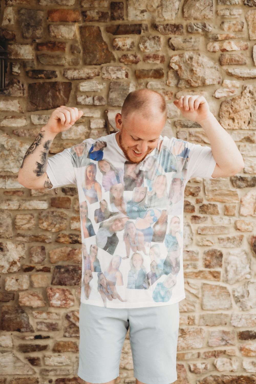Person wearing a photo collage t-shirt poses playfully against a rustic brick wall.