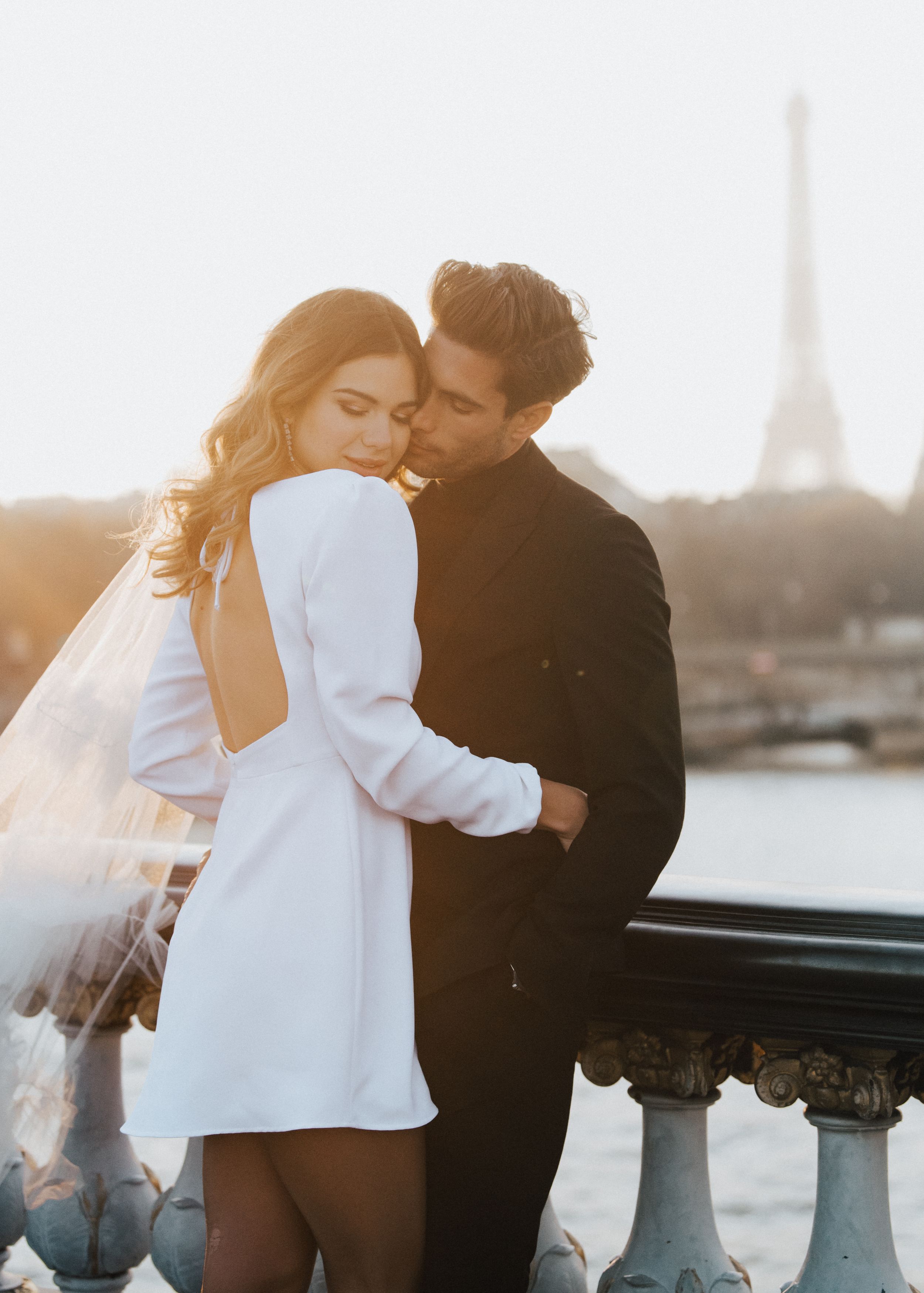 A romantic moment captured at sunset with the Eiffel Tower visible in the background.