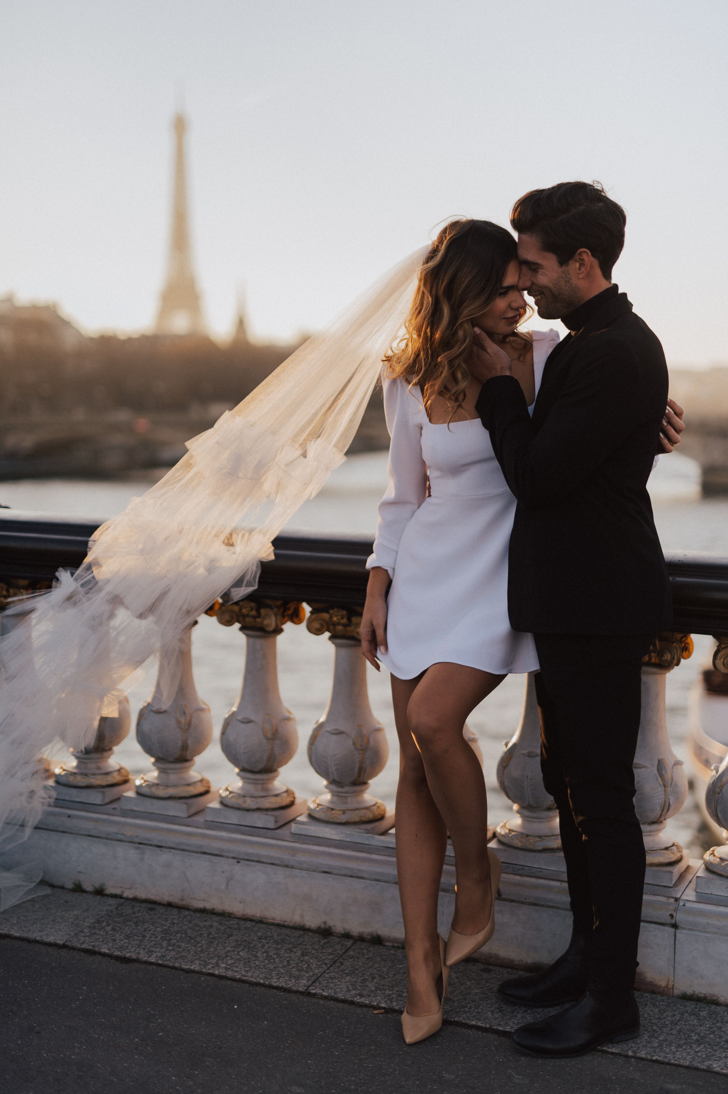 A romantic photoshoot on a Paris balcony with ornate stone railings.