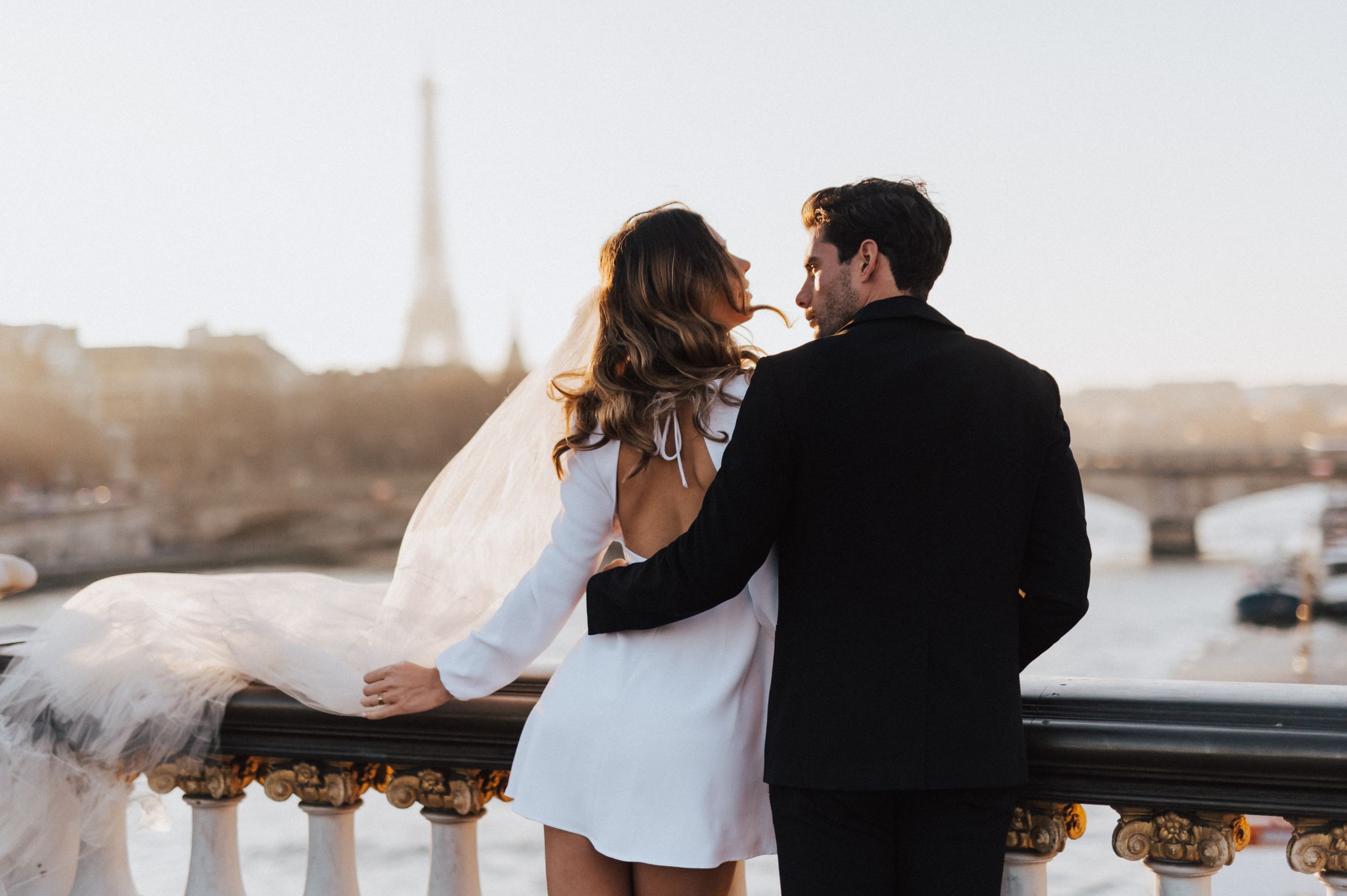 A couple shares an intimate moment on a Parisian balcony at golden hour.
