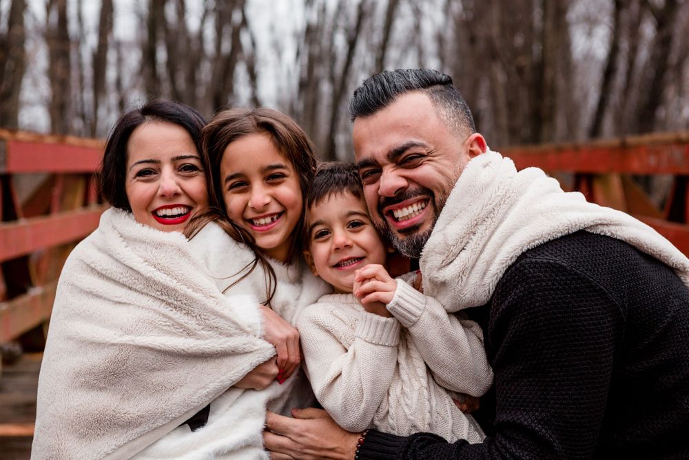 A family shares warm embraces on a wooden bridge during winter.