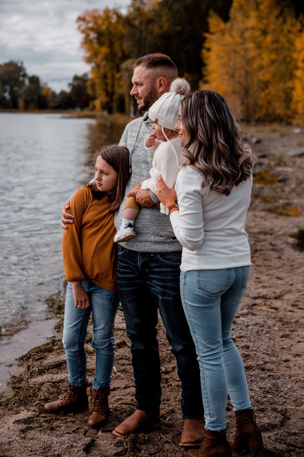 A family enjoying a tender moment together on an autumn lakeshore.