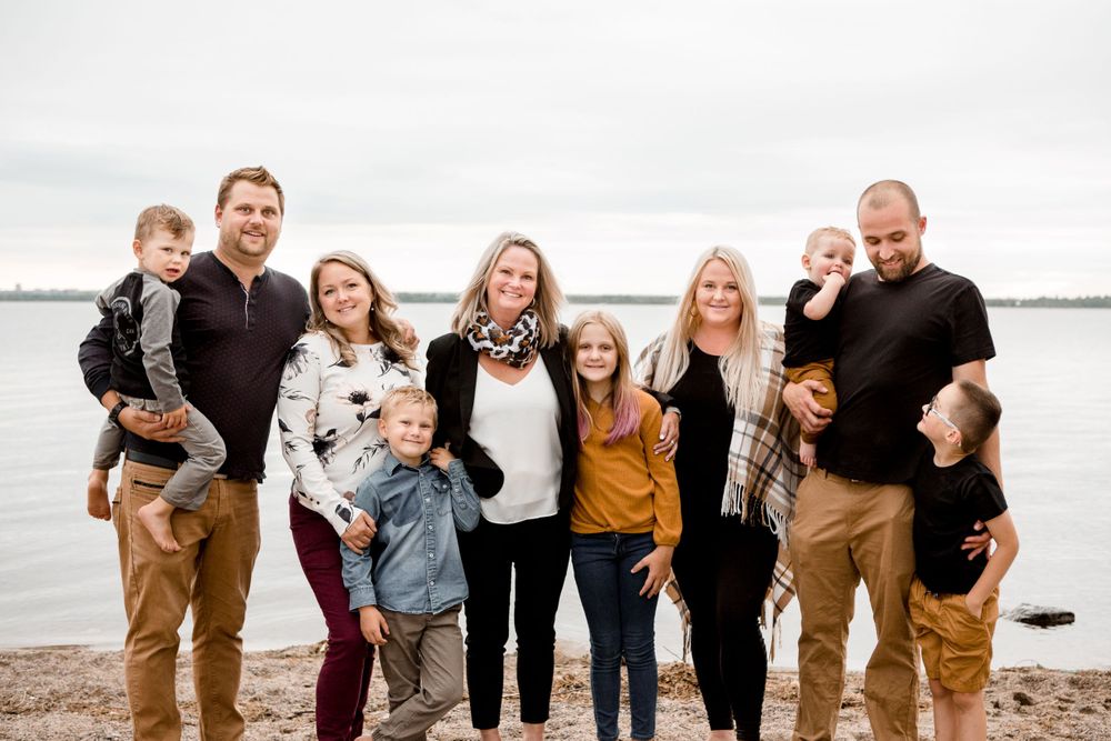 A large extended family posing together by a lakeside on an overcast day.