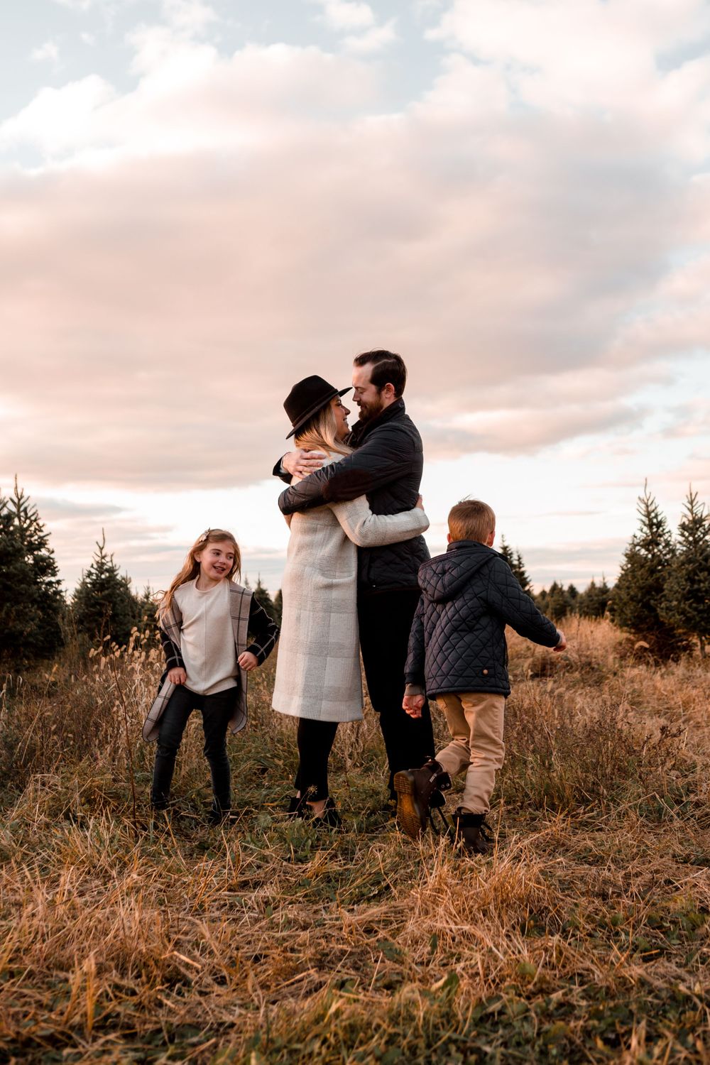 A family shares playful moments together in a field during sunset.