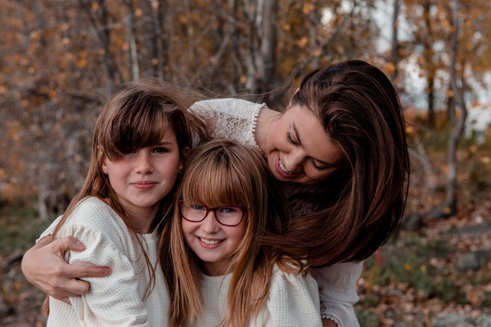 Family members share warm hugs and laughter in an autumn setting.