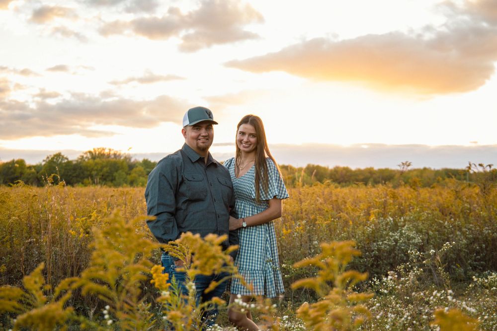 Couple walking through wildflower field during golden hour sunset.