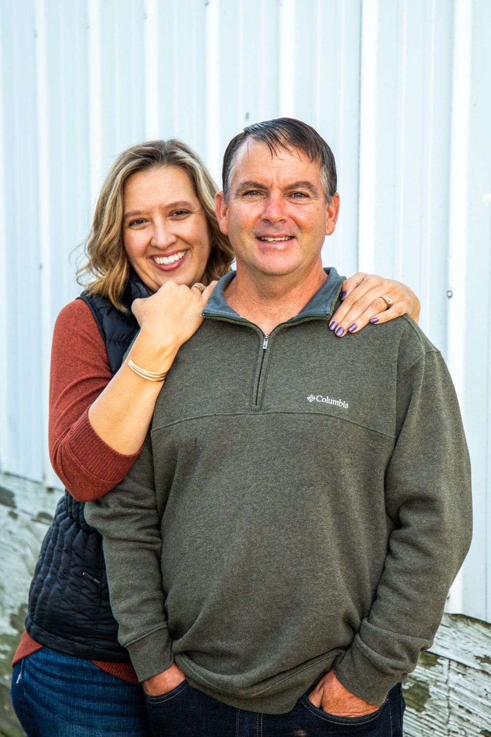Casual couple in warm sweaters sharing candid moments against a white wall backdrop.