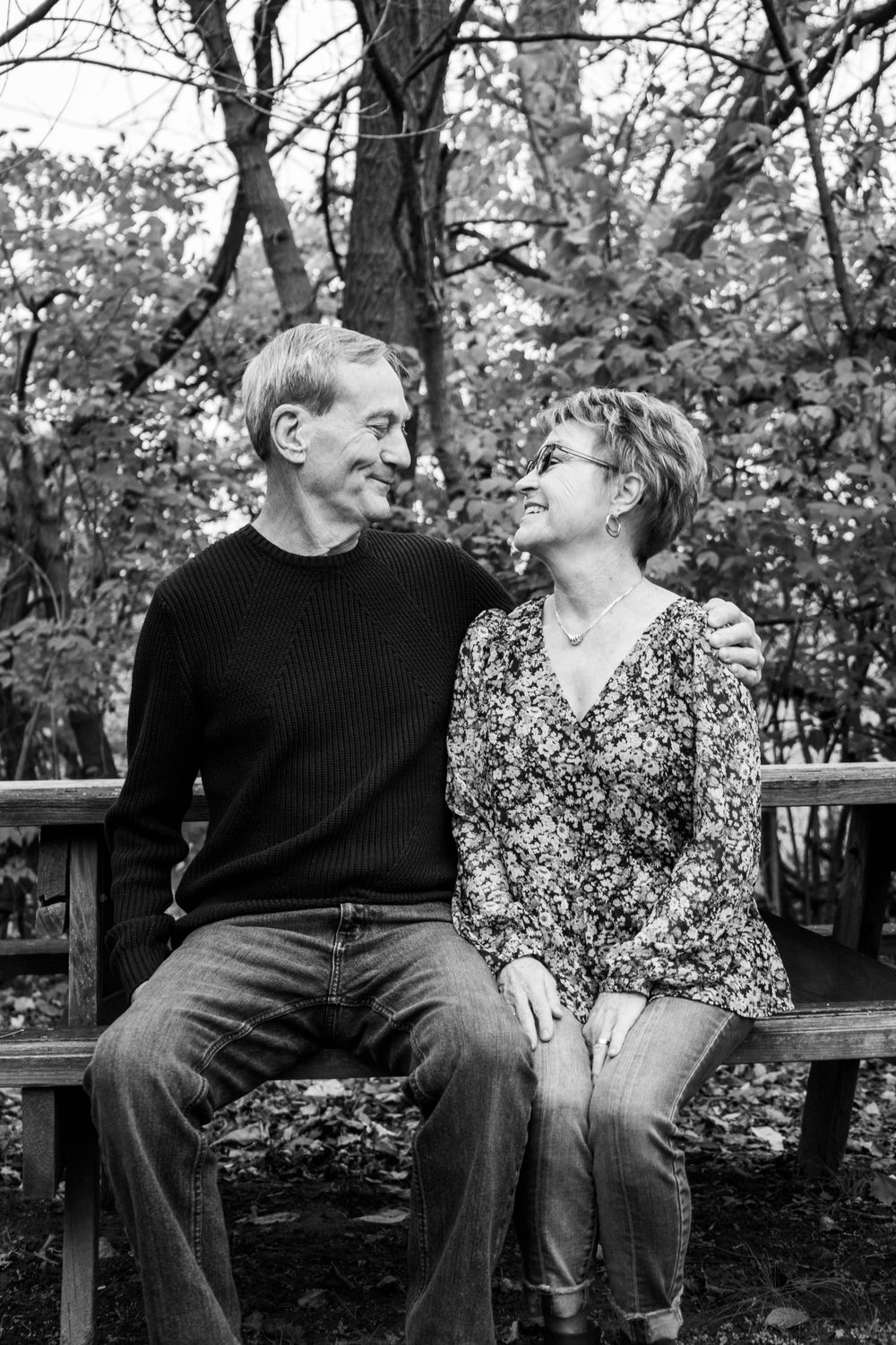 Black and white portrait of couple sharing intimate moment on park bench.