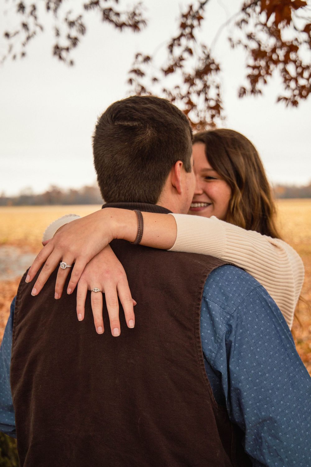 Couple in autumn clothing sharing intimate embrace outdoors at sunset.