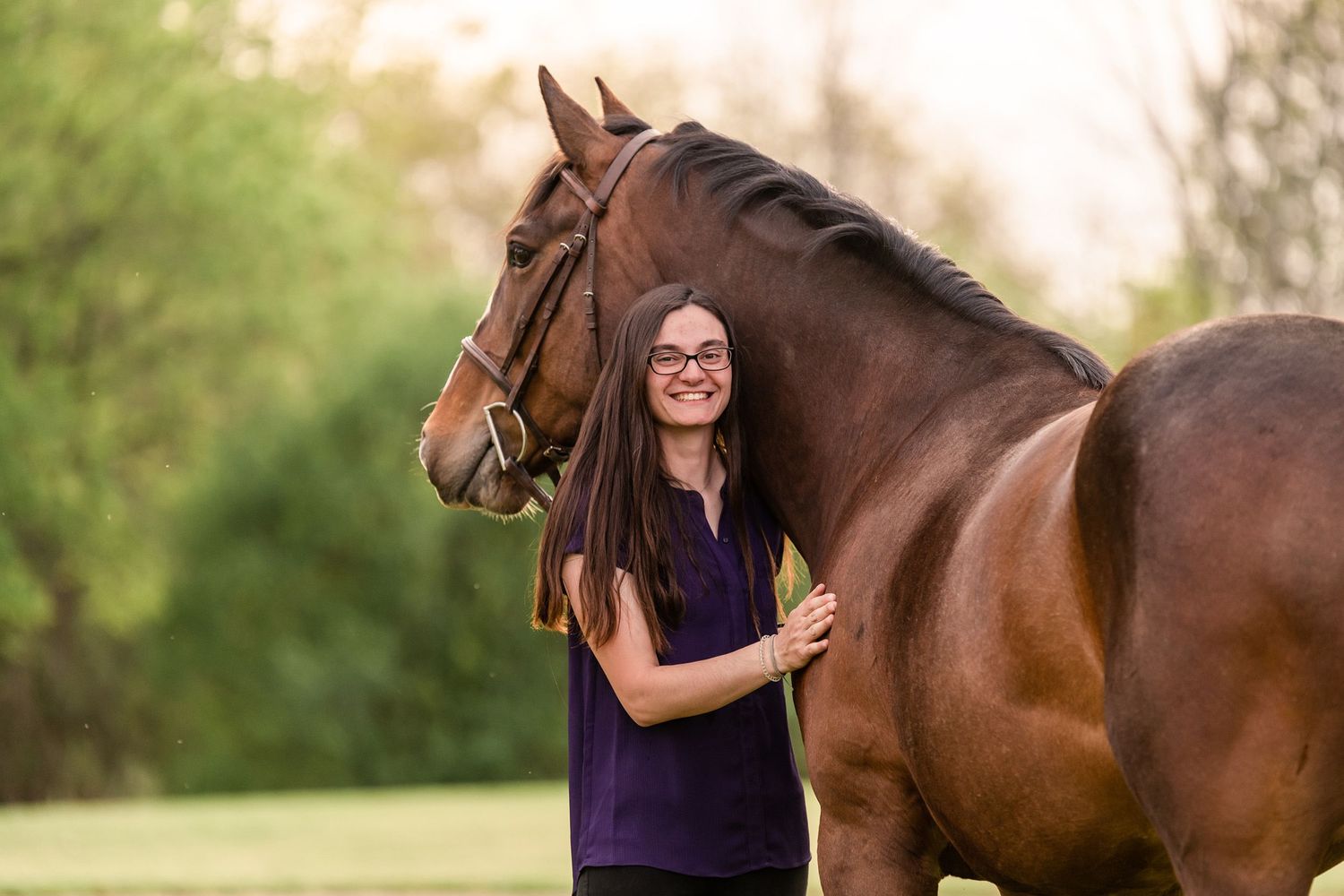 Girl in purple shirt with a bay draft cross horse