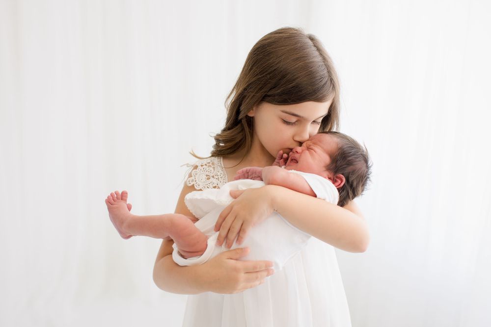 Sweet moment with person in white dress cradling and kissing newborn baby.