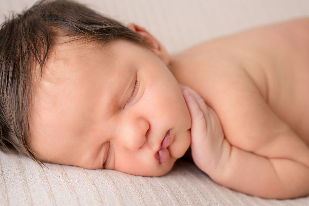 Close-up of peaceful sleeping newborn baby against soft white background.