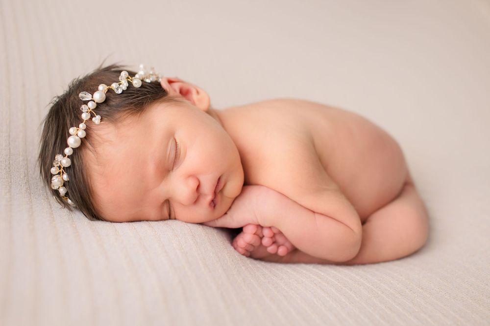 Artistic portrait of sleeping newborn with floral crown in natural light.
