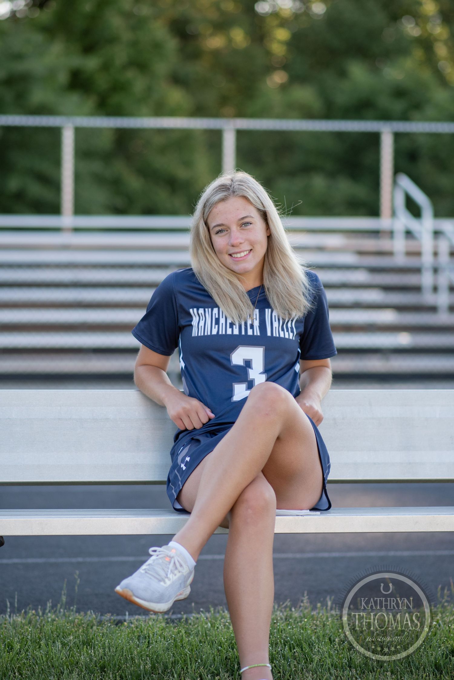 Student athlete wearing jersey number 3 sits casually on stadium bleachers.