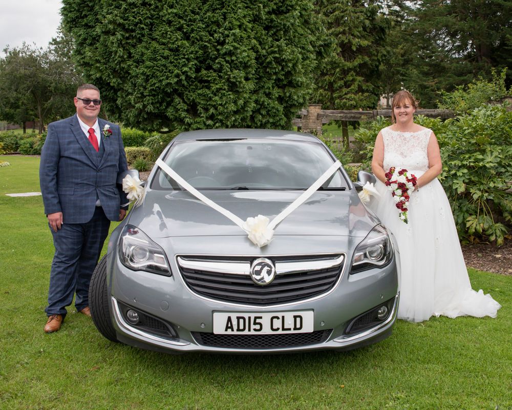 Silver Mercedes-Benz car decorated for a wedding celebration in a garden setting.