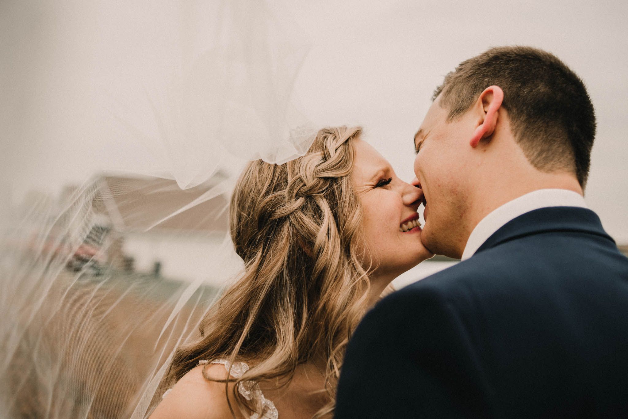Intimate close-up wedding portrait with bride's veil flowing in the wind.