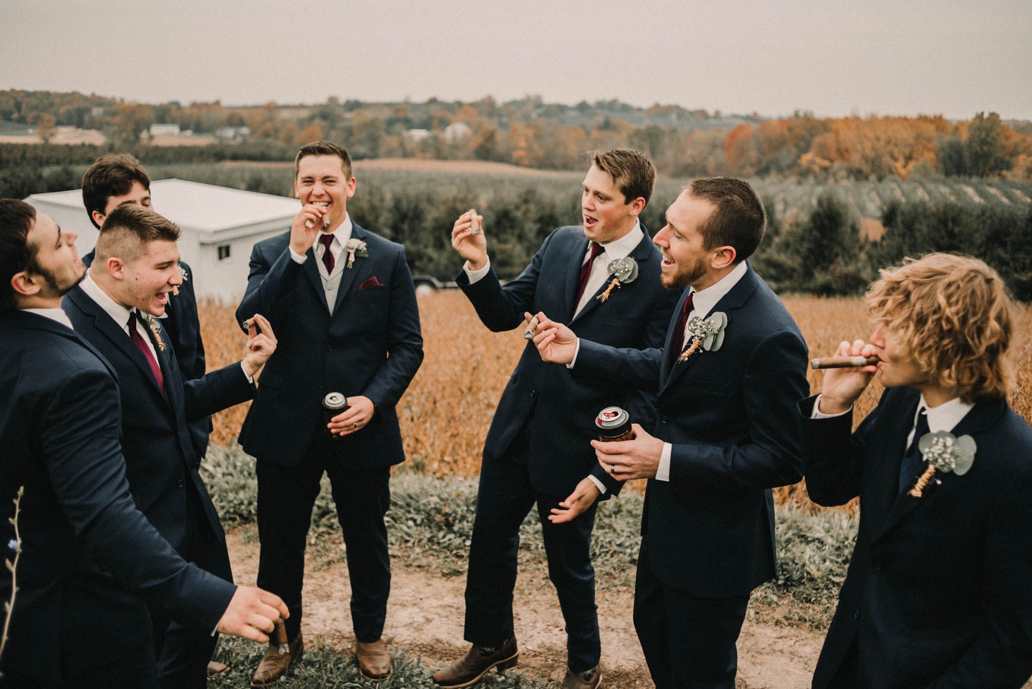 Groomsmen sharing laughs and celebrations in an autumn field.