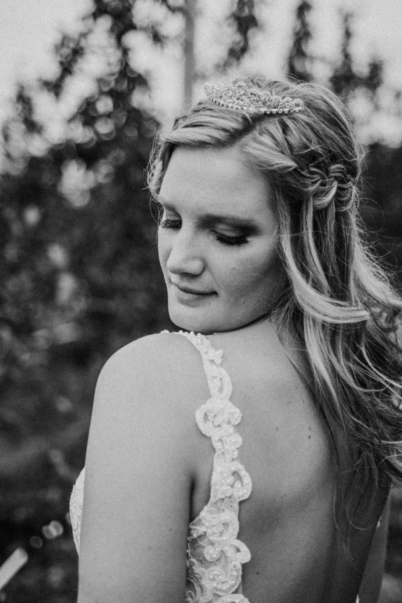 Black and white bridal portrait showcasing delicate lace straps and braided hairstyle with crystal headpiece.