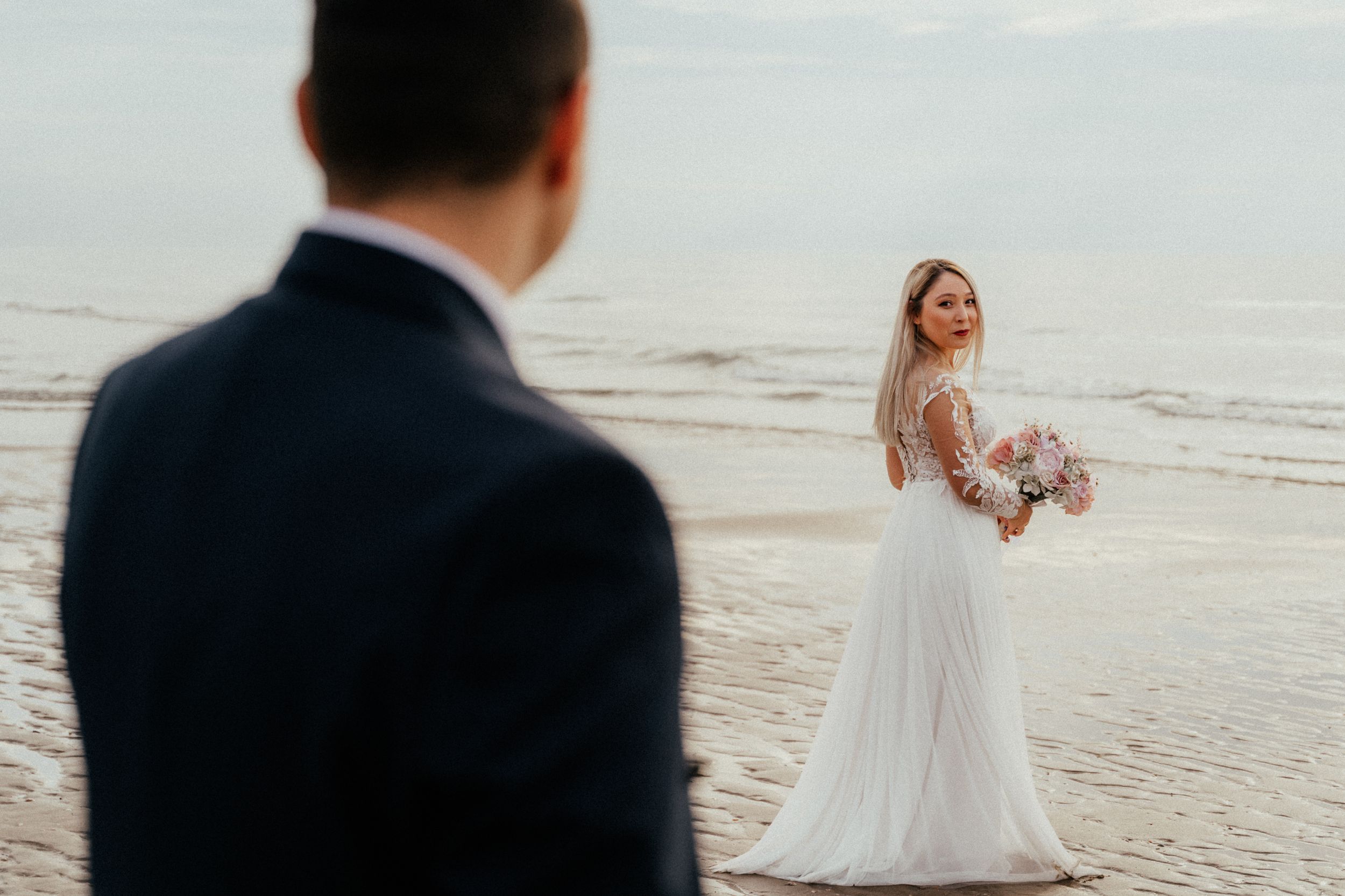 A bride smiling while holding a beautiful bouquet of flowers