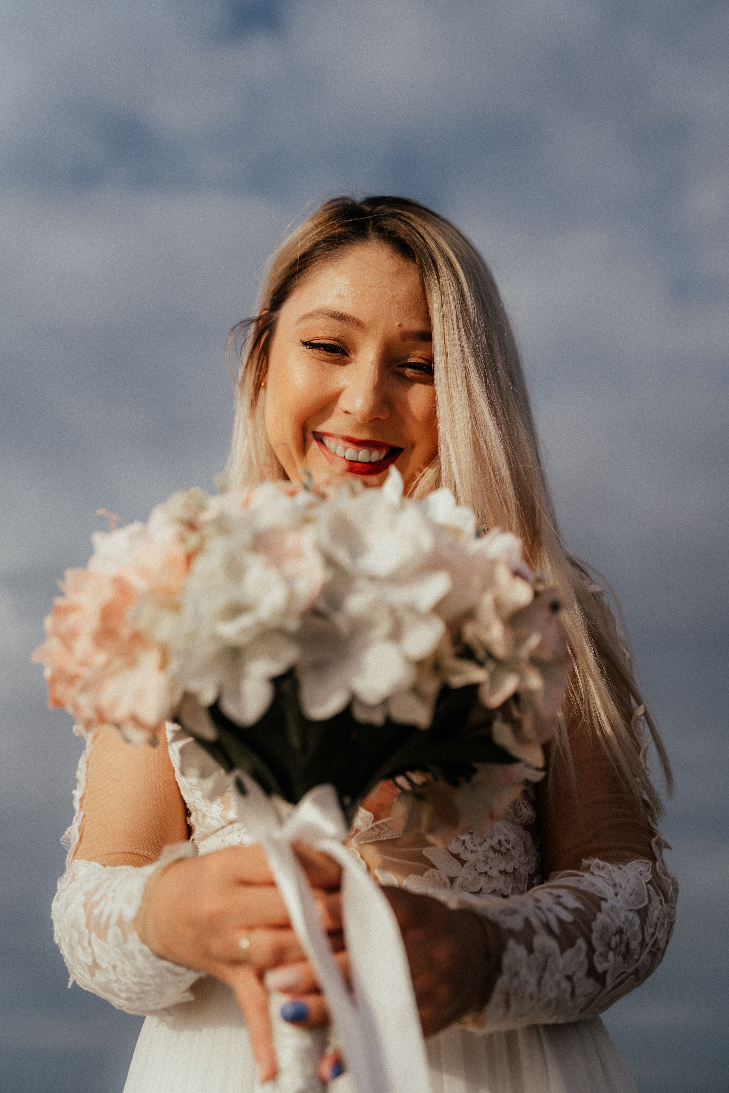A woman smiling while holding a beautiful bouquet of flowers, bringing joy and color to her surroundings.