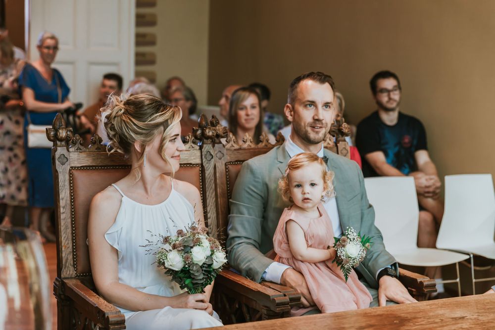 Intimate wedding ceremony in church with family members watching from wooden pews.