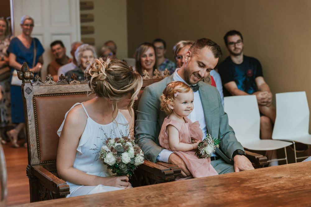 Small family wedding ceremony in a church with natural light streaming through windows.