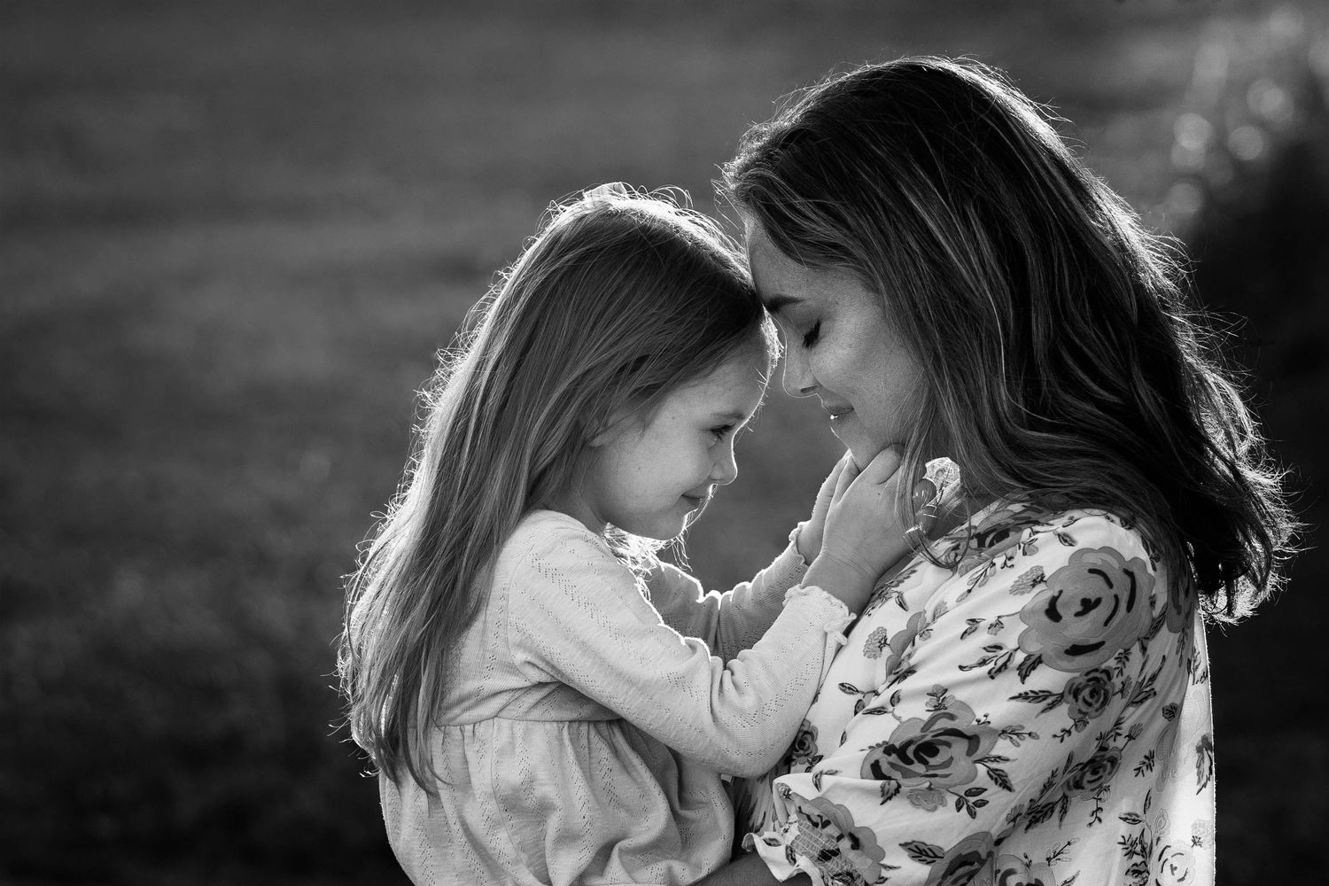 black and white portrait of mom holding little girl and touching foreheads