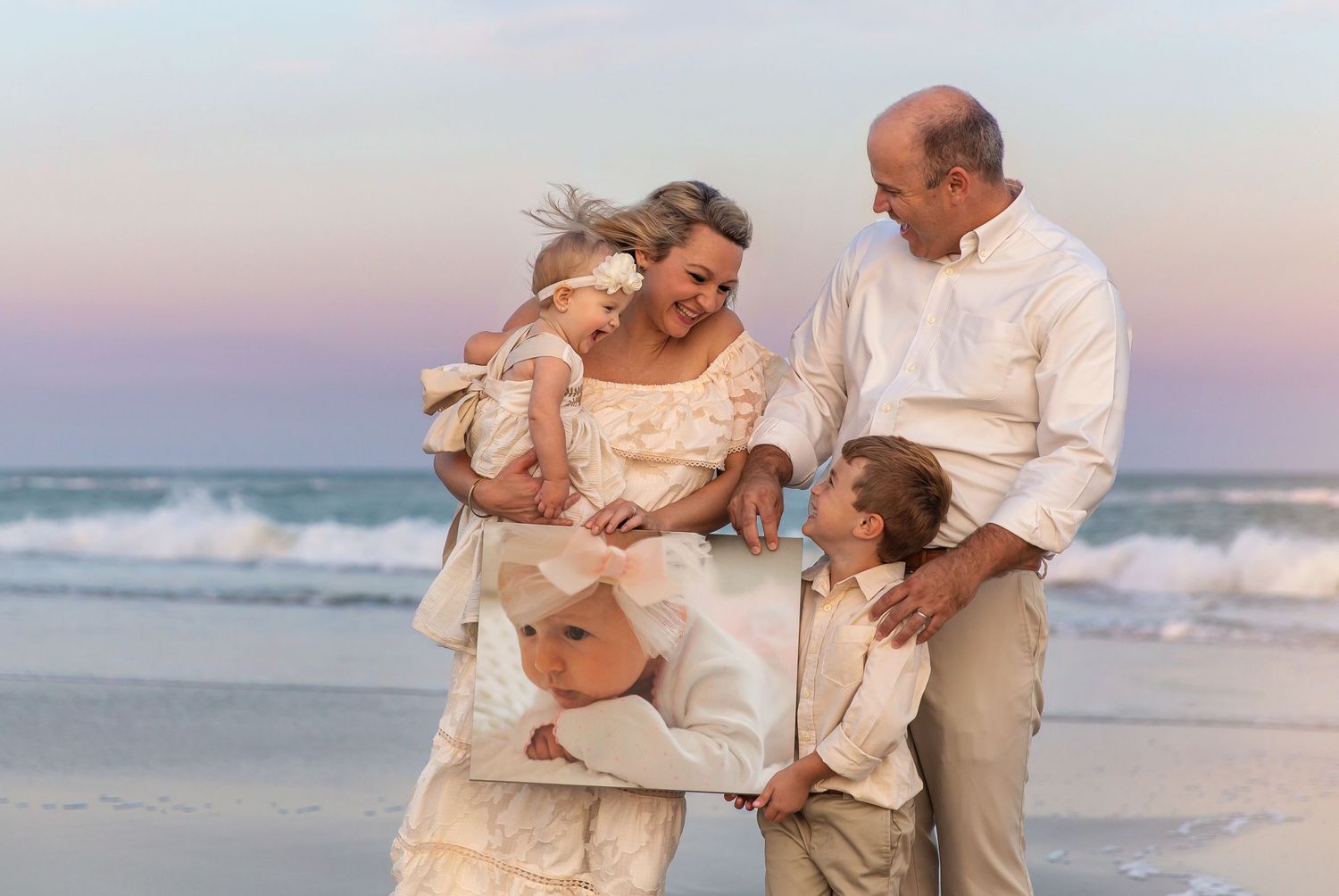 Family gathering on beach at sunset wearing white and cream colored clothing.