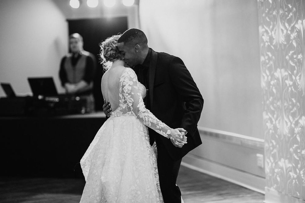 Black and white photo of bride and groom sharing a romantic first dance at their wedding reception.