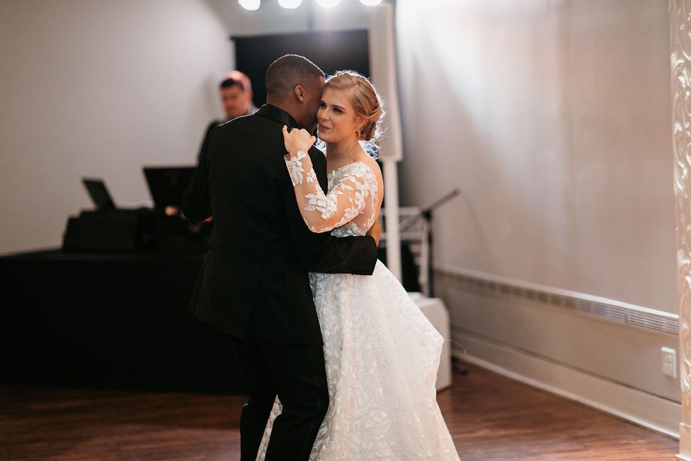 Bride and groom dancing closely together during their first dance at an elegant wedding reception.