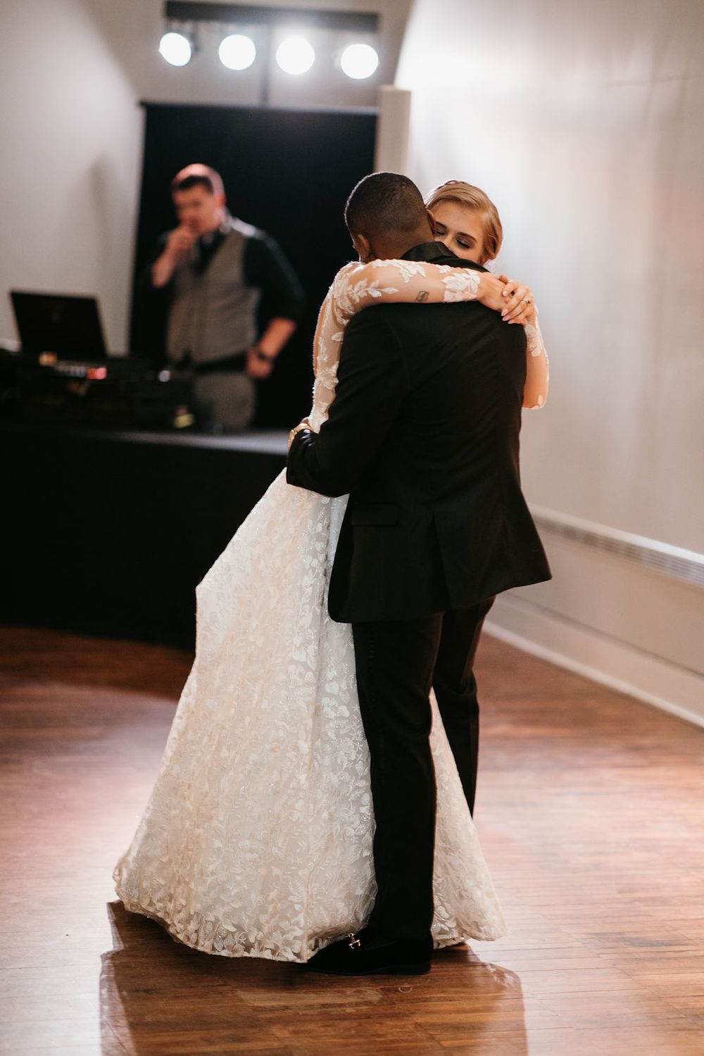 Newlywed couple share a tender hug during their first dance at wedding reception.